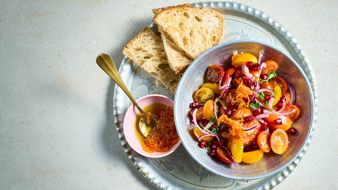 Tomatensalade met Perzische worteldressing en toast op een zilveren dienblad.