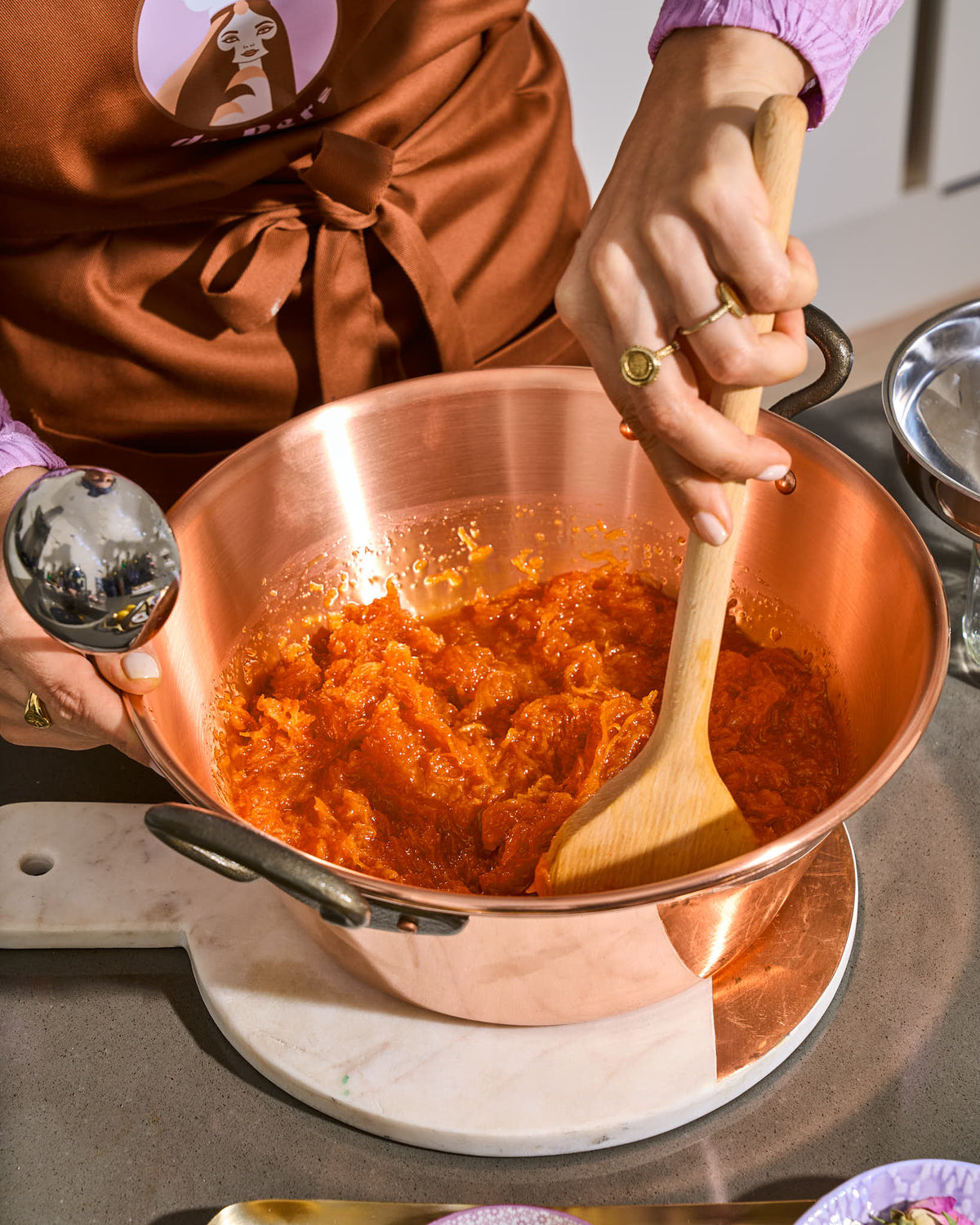 hand roert met pollepel in een koperen pan met Wortel Wonder (Perzische worteljam)